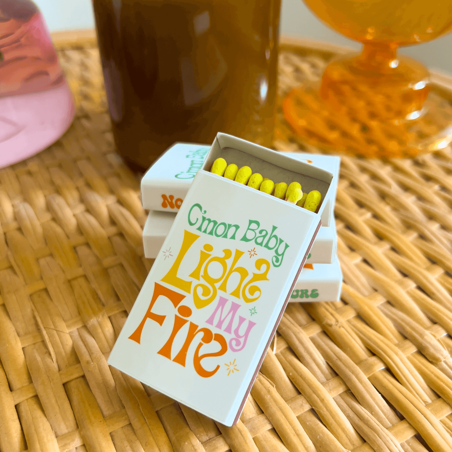 Matchbox on wicker table with come on baby light my fire text graphic. Yellow tipped matches