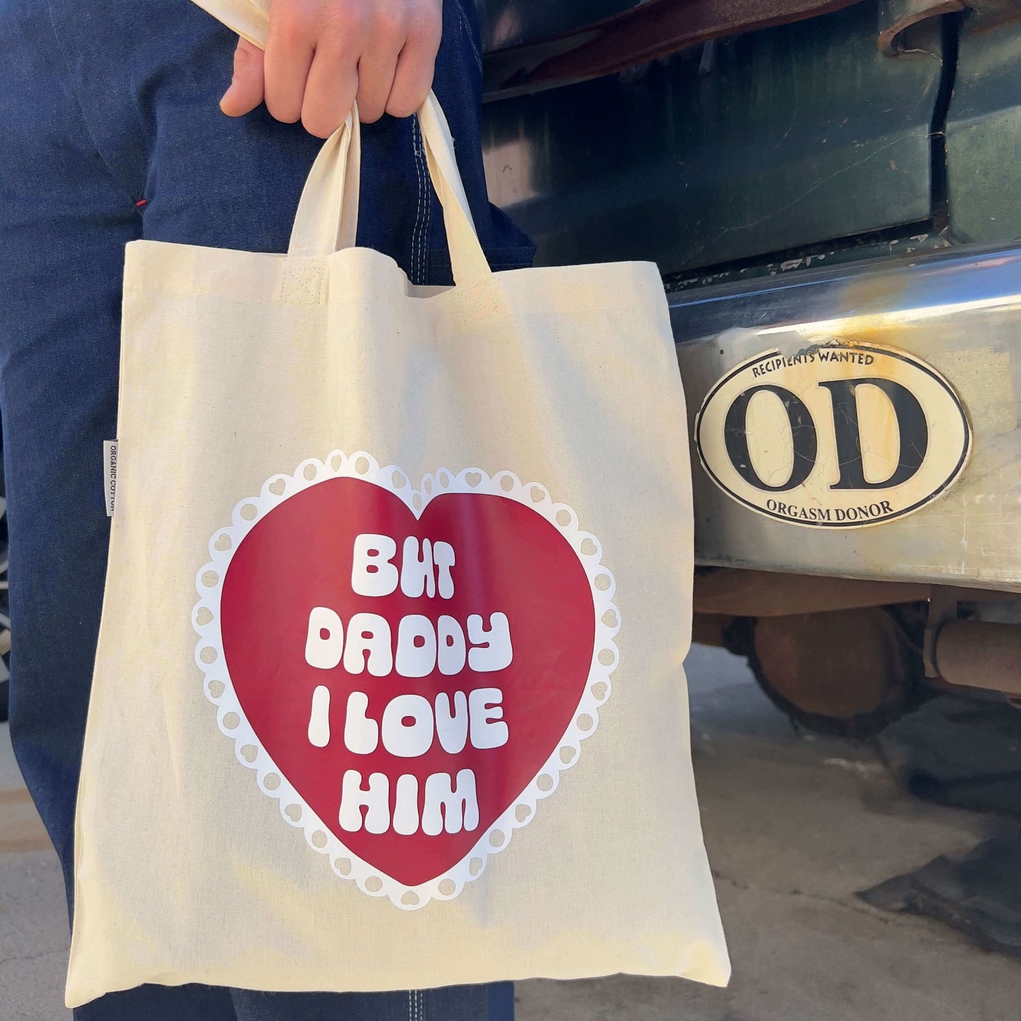 model holding tote bag in front of old van