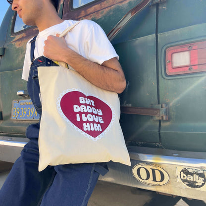 guy sitting on a bumper wearing but daddy i love him tote bag