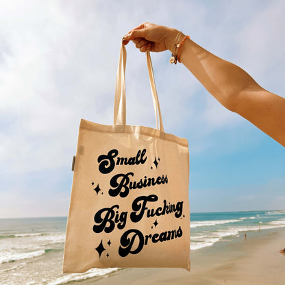 small business big fucking dream tote bag hanging in front of the beach shore
